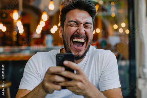 Exhilarated man with a fist pump celebrating while looking at his smartphone, indoor setting with soft background lights.