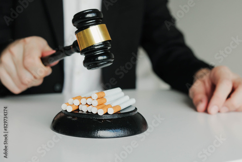 Judge hitting cigarettes with referee's gavel on white table. Tobacco law. photo