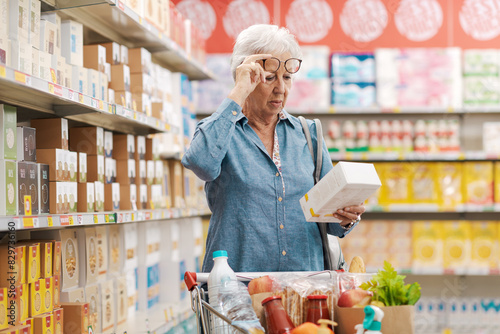 Senior woman with vision problems reading information on a product package at the supermarket