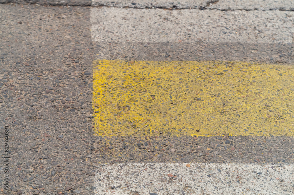 Fototapeta premium Edge of pedestrian crossing with strips of road reflective paint yellow and white colors, wear of the road surface and additional signals on the carriageway