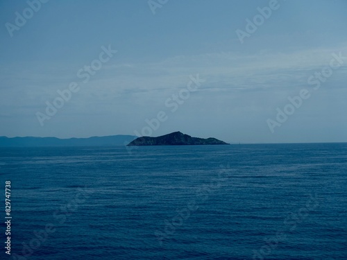 Scenic ocean view with a small island surrounded by blue water © Wirestock