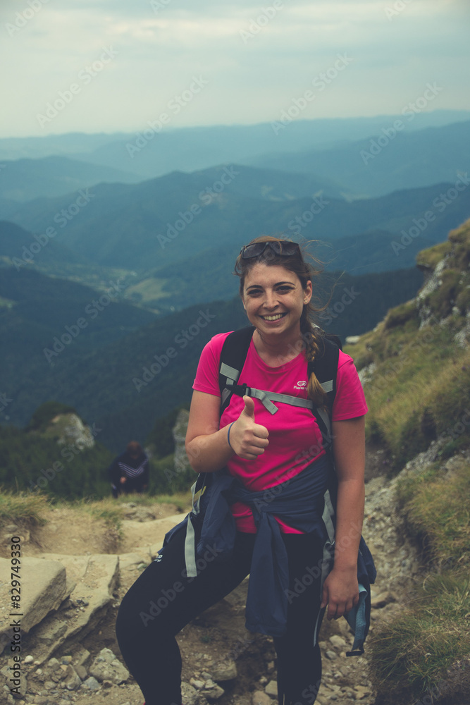 Smiling woman posing on top of a green mountain on a cloudy day Smiling woman posing on top of a green mountain on a cloudy day