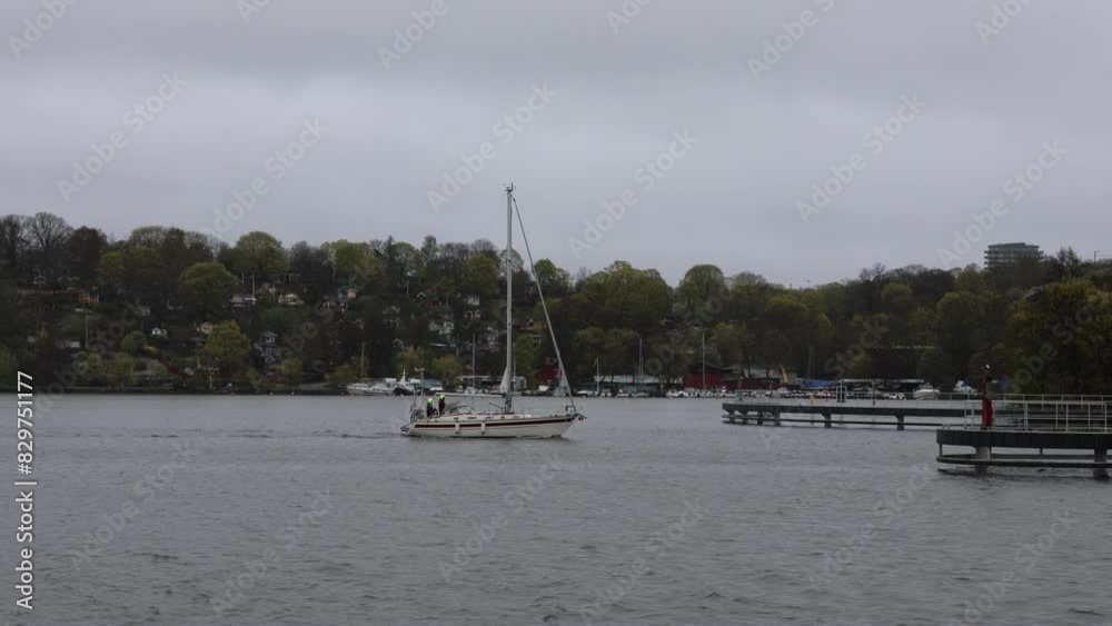 Lone motor sailboat near a pier in Arstaviken Stockholm Sweden on a gray rainy day Lone motor sailboat near a pier in Arstaviken Stockholm Sweden on a gray rainy day