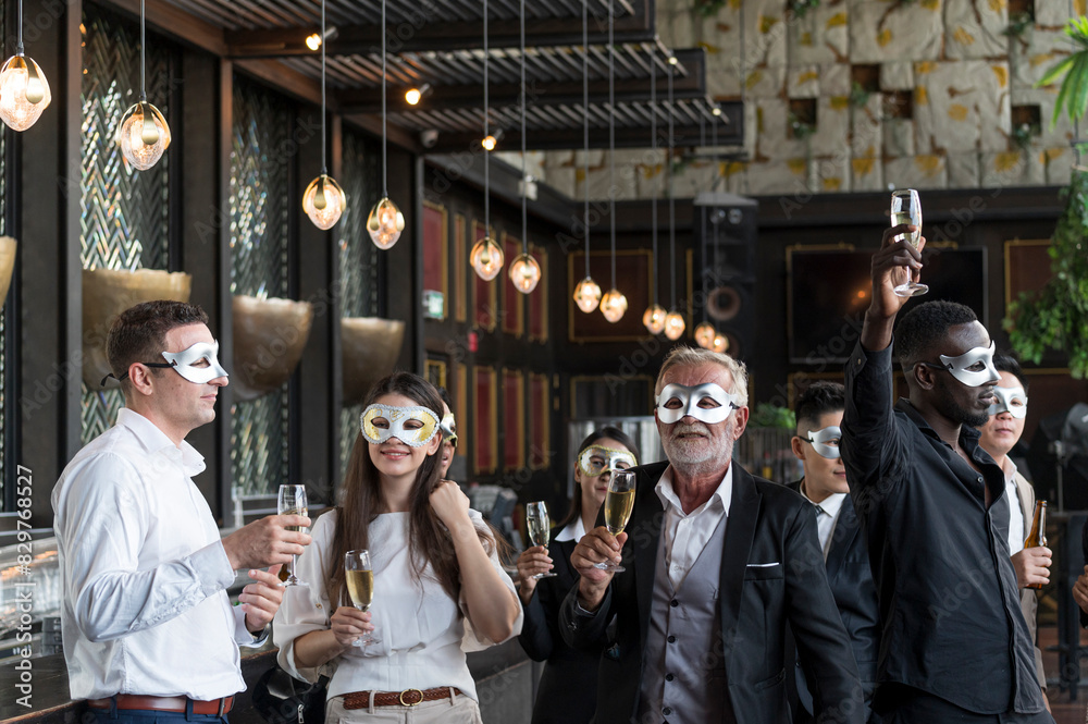 Obraz premium Group of diverse friends toasting with clinking champagne glasses at funny and happy Christmas and new year mask party atmosphere. Holiday celebrate and nightlife lifestyle concept