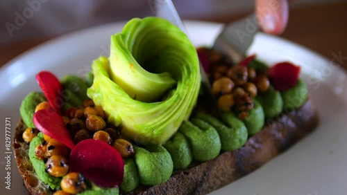 Close-up knife and fork cutting toast with avocado, vegetables and legumes Healthy and satisfying breakfast option. Breakfast looks delicious and fresh Nutritious breakfast healthy and tasty start day