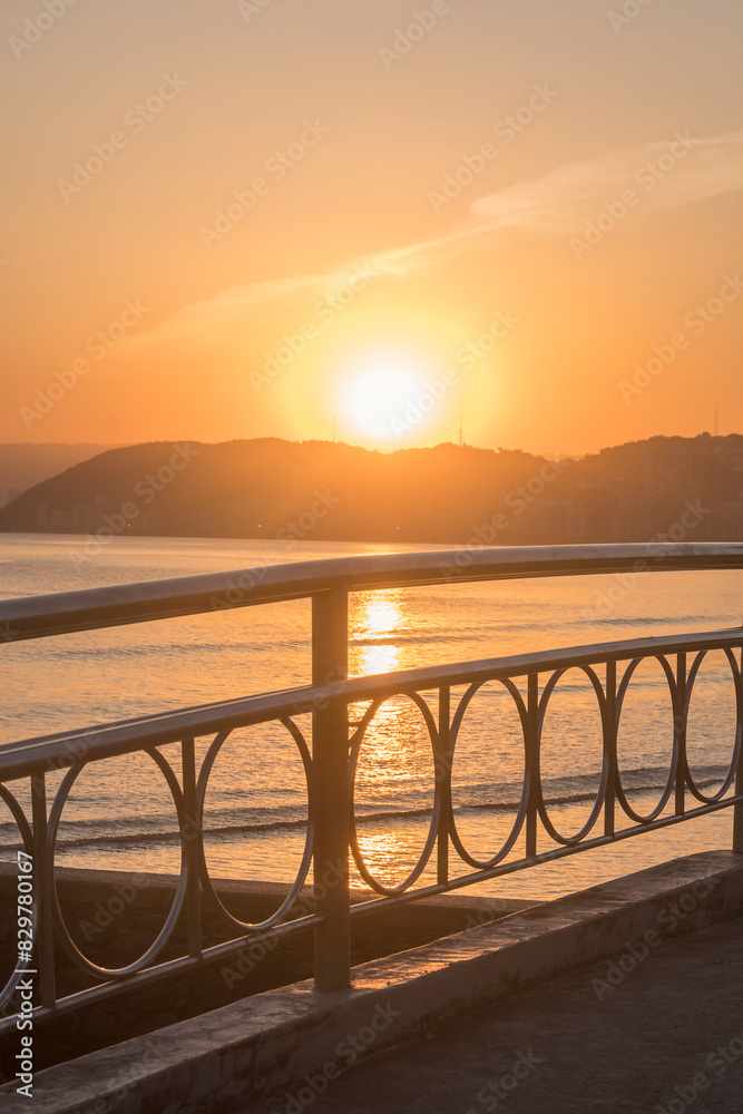 Obraz premium Sunset on the beach in the City of Santos, Brazil. The handrail railing of the bridge over the water channel.