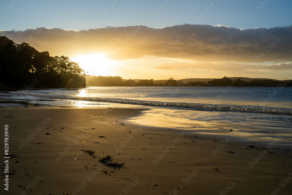 sunrise reflecting on the beach with golden light as waves roll in and water moves on the sand, calming waves sunrise reflecting on the beach with golden light as waves roll in and water moves on the sand, calming waves
