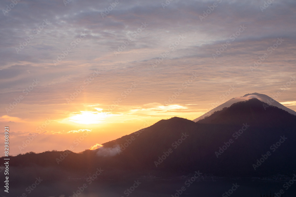 Sunrise over Mount Batur with a golden sky and silhouetted mountains. Travel Sunrise over Mount Batur with a golden sky and silhouetted mountains. Travel