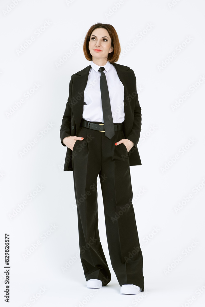 Portrait of a confident business woman in a black pantsuit and a white blouse on a white background. Full-length portrait of a middle-aged woman in black trousers Portrait of a confident business woman in a black pantsuit and a white blouse on a white background. Full-length portrait of a middle-aged woman in black trousers
