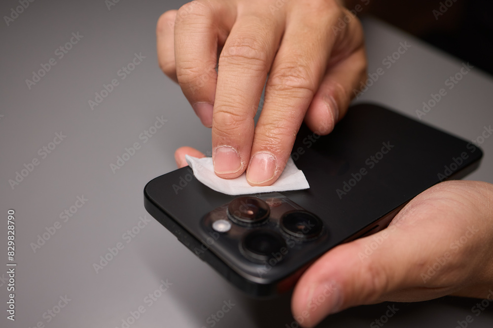 A person is wiping a cell phone clean with a tissue A person is wiping a cell phone clean with a tissue
