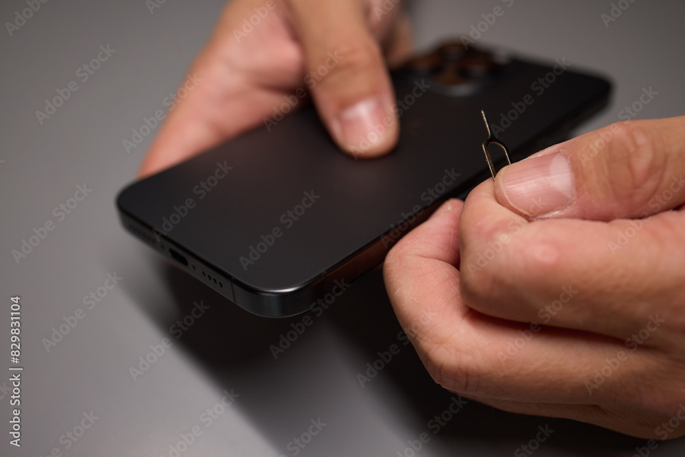 A person is inserting a sim card into a cell phone using hand and fingers A person is inserting a sim card into a cell phone using hand and fingers