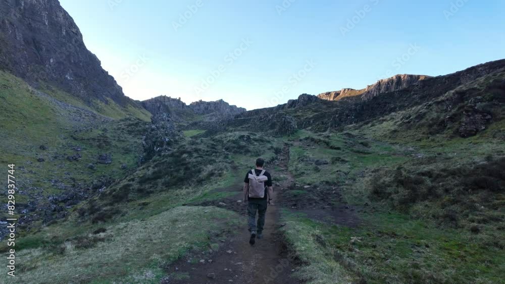 Hiker exploring the rugged landscape of Isle of Skye's Quiraing at sunrise Hiker exploring the rugged landscape of Isle of Skye's Quiraing at sunrise