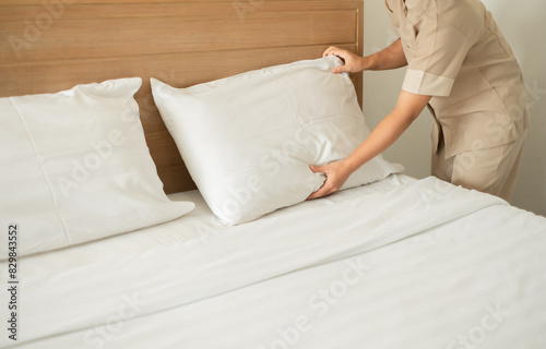 The hotel maid cleans and makes the bed in the hotel room