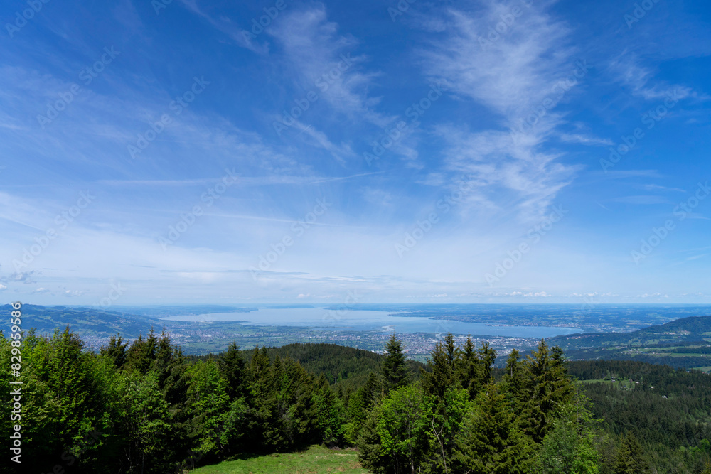 View from high up on a mountain over a forest onto a blue lake and the shore 