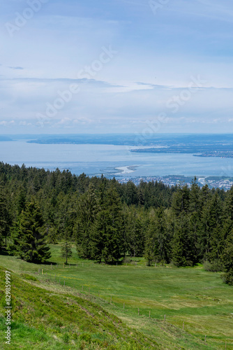 View from high up on a mountain over a forest onto a blue lake and the shore 