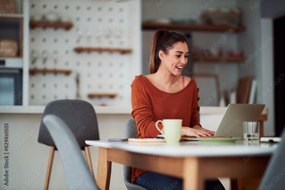 A cheerful young adult woman typing on her laptop and working from home A cheerful young adult woman typing on her laptop and working from home