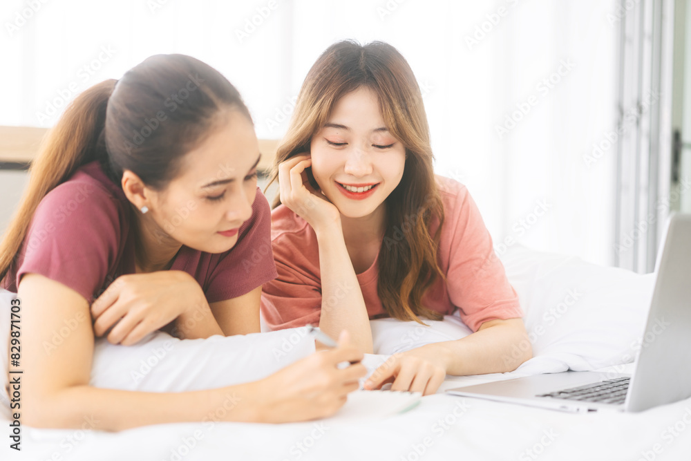 Two young adult woman living together with relationship laying at bedroom talking in the morning Two young adult woman living together with relationship laying at bedroom talking in the morning