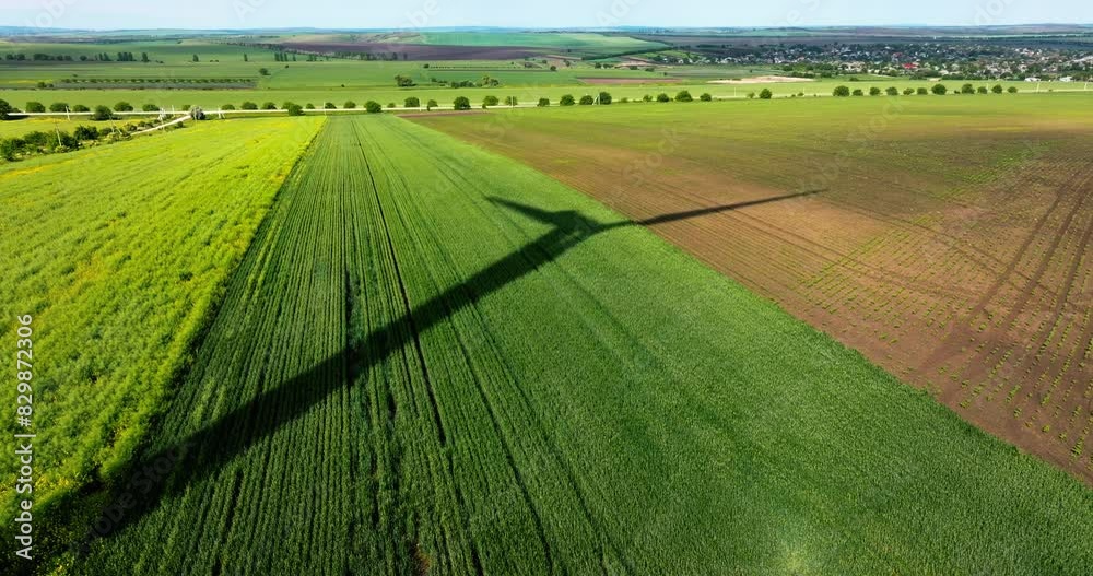 Aerial drone view of a wind turbine shadow on an agricultural field