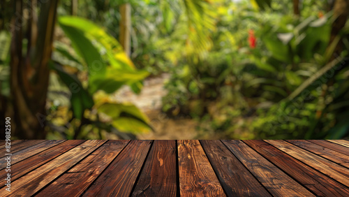 Empty wood table top with blur background of tropical jungle in summer green. The table giving copy space for placing advertising product on the table along with beautiful forest banner background.