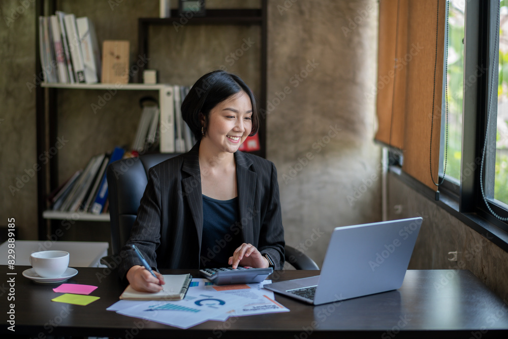 A woman is sitting at a desk with a laptop and a calculator A woman is sitting at a desk with a laptop and a calculator