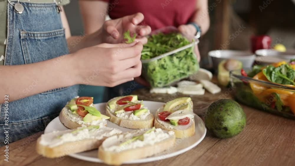 little girl with her mother cooking healthy sandwiches with cheese and vegetables for the breakfast