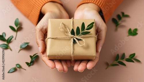 Female hands holding wrapped brown package gift box made of natural corrugated cardboard. simple and clean solid color background. packaging, shopping, delivery concept.