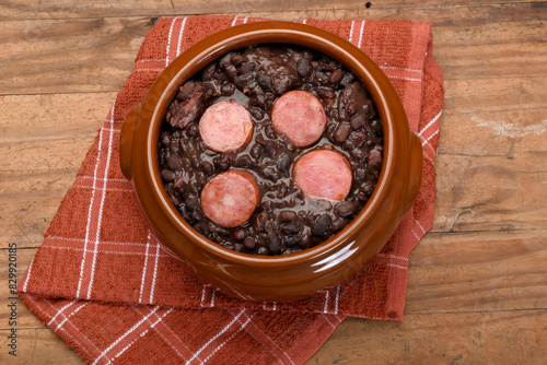 FEIJOADA IN A BROWN BOWL ON A WOODEN BASE, CABBAGE, 