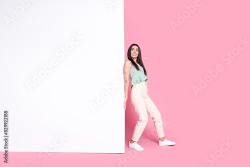 Photo of funny adorable woman dressed trendy clothes push heavy poster empty space isolated on pink color background