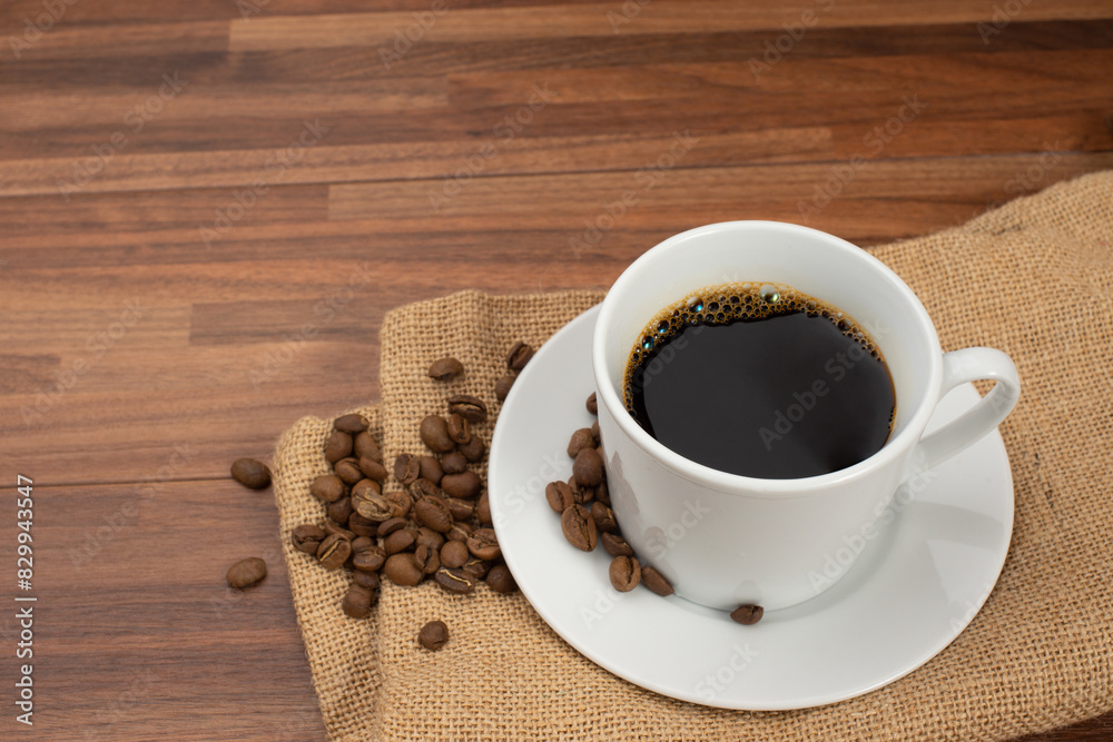 木目テーブルの上に置かれたコーヒーカップとコーヒー豆 木目テーブルの上に置かれたコーヒーカップとコーヒー豆