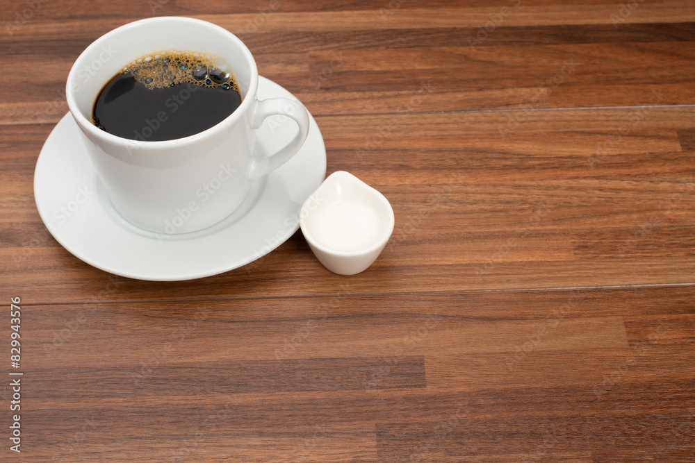 木目テーブルの上に置かれたコーヒーカップとコーヒーフレッシュ 木目テーブルの上に置かれたコーヒーカップとコーヒーフレッシュ