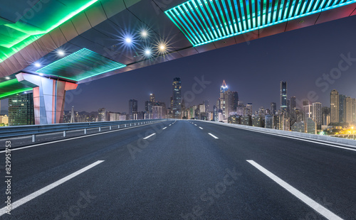 Asphalt highway road and bridge with modern city buildings at night