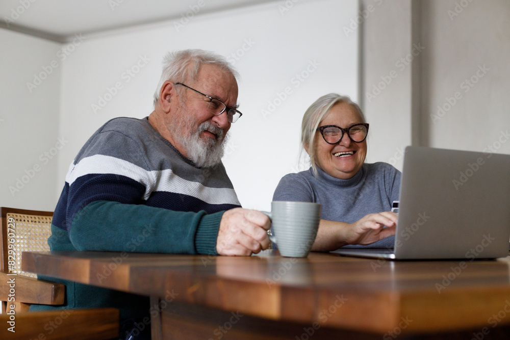 Fototapeta premium Distraught senior couple e-banking with credit card and laptop at home.