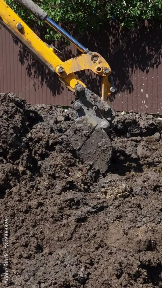 Vertical video. A tractor move dark brown ground using bucket. Vehicle dig earth from one side, lift up and turn boom and fills the hole from the other side. Ground works Vertical video. A tractor move dark brown ground using bucket. Vehicle dig earth from one side, lift up and turn boom and fills the hole from the other side. Ground works