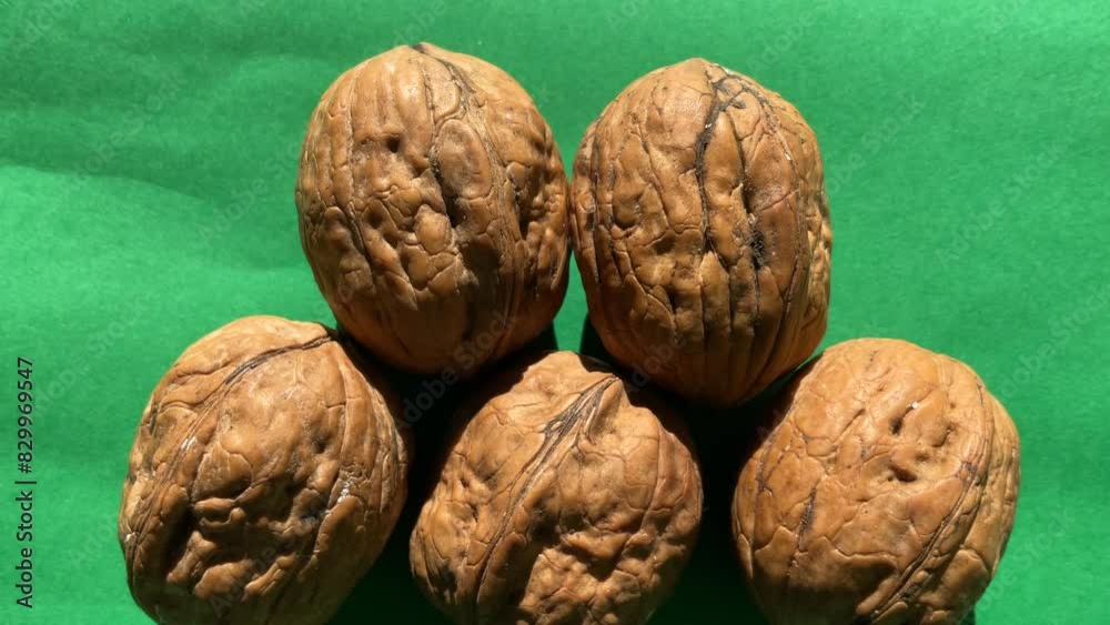 Slow upward pan of walnuts on green background Slow upward pan of walnuts on green background