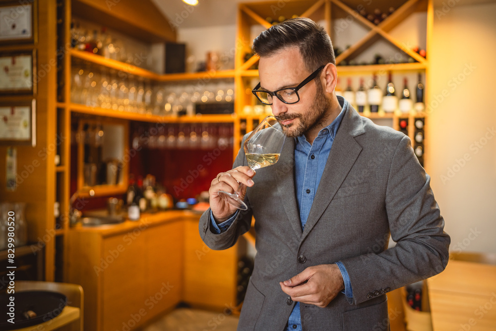 Adult man stand in a winery and smell glass of wine