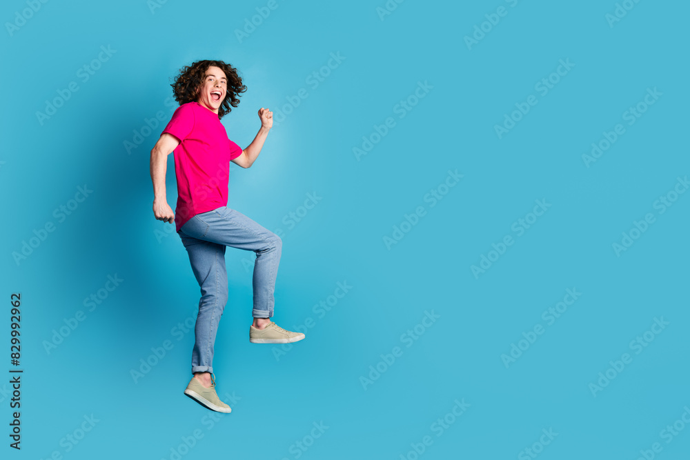 Full length portrait of nice young man jump rush empty space wear t-shirt isolated on blue color background Full length portrait of nice young man jump rush empty space wear t-shirt isolated on blue color background