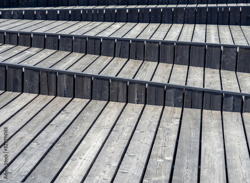 Wooden deck background. Floor and wall wood texture background. Seating benches are part of a staircase which is built of dark gray planks. Asymmetric stair treads 