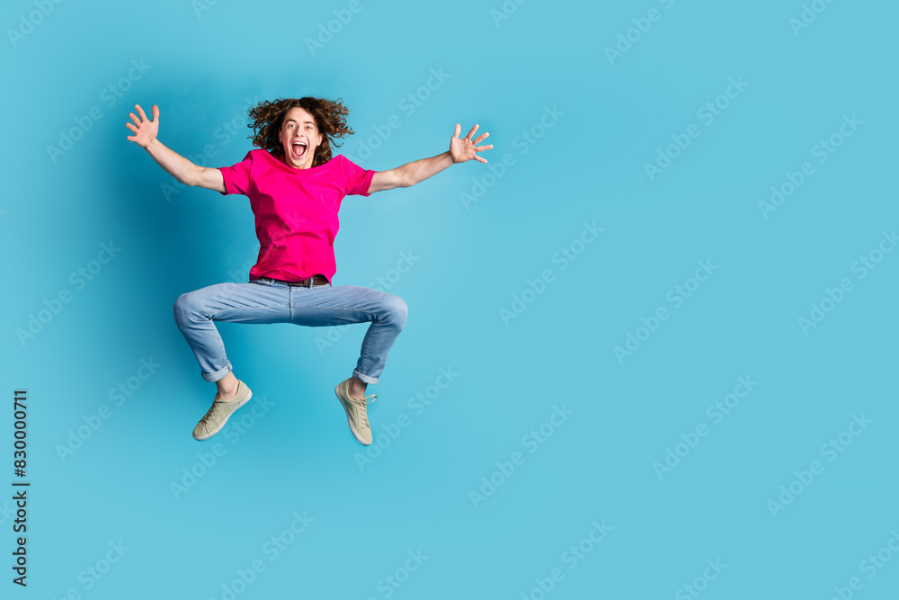 Full length portrait of nice young man jump empty space wear t-shirt isolated on blue color background