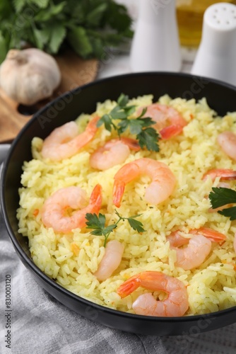 Delicious risotto with shrimps and parsley in bowl on table, closeup