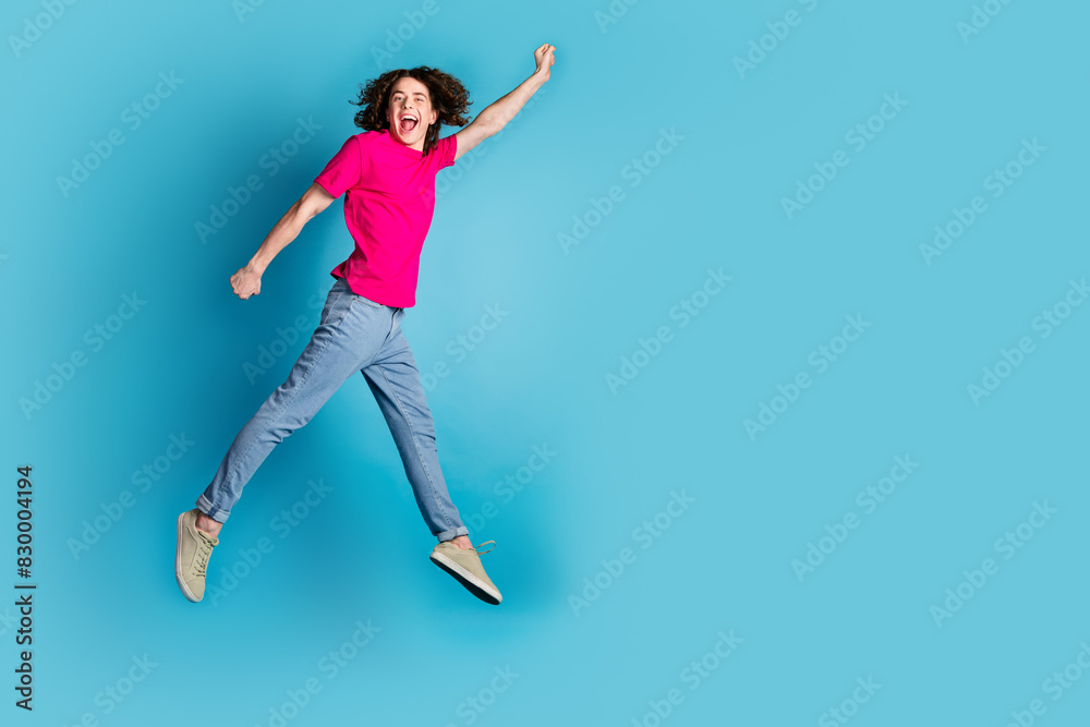 Full length portrait of nice young man jump empty space adwear t-shirt isolated on blue color background