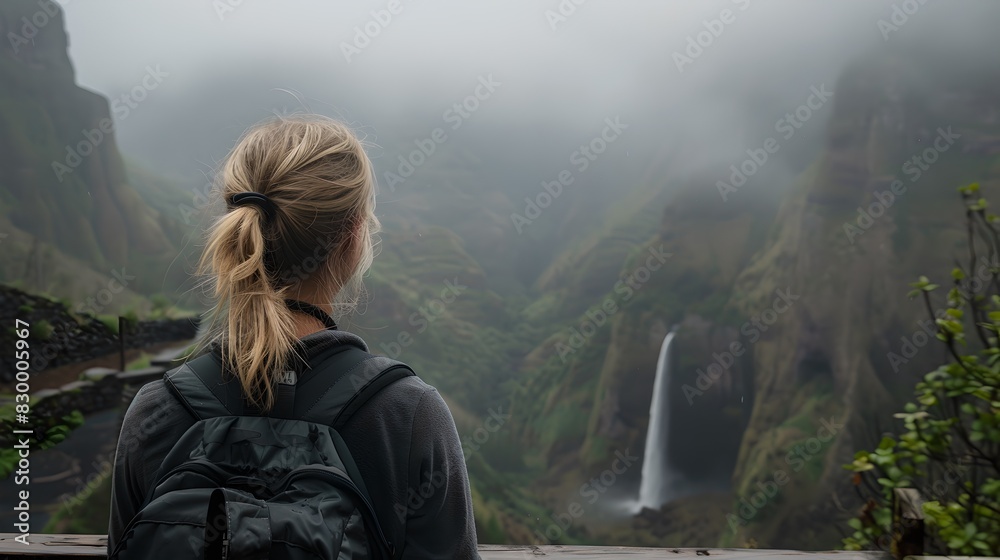 Woman stands in front of a misty waterfall in a mountainous area. Scenic view of nature. Adventure travel inspiration. AI Woman stands in front of a misty waterfall in a mountainous area. Scenic view of nature. Adventure travel inspiration. AI