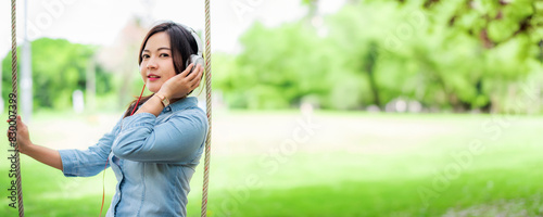 Young carefree attractive Asian woman enjoy to listening music in garden