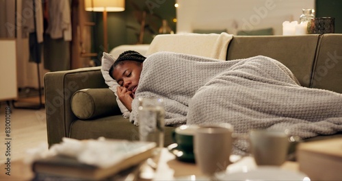 Woman, sick and sneezing with blanket on sofa for blowing nose, recovery and winter virus in living room. Black person, infection or ill with fever, sinus and allergy on couch in home with healthcare © peopleimages.com