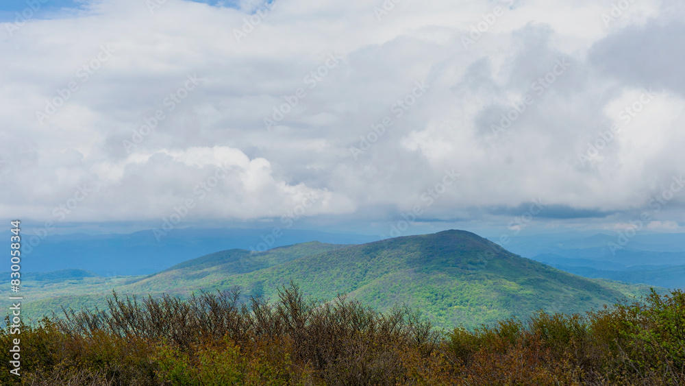 The south summit view from the peak of Elk Knob in North Carolina. Heavy white clouds hang over the Unicoi Mountain range in the foreground and the blue ridge mountain's layered peaks in the distance. The south summit view from the peak of Elk Knob in North Carolina. Heavy white clouds hang over the Unicoi Mountain range in the foreground and the blue ridge mountain's layered peaks in the distance.