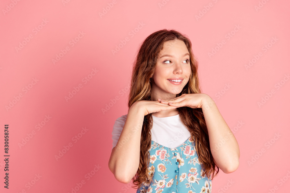 Portrait of lovely young girl hands under chin look empty space wear dress isolated on pink color background Portrait of lovely young girl hands under chin look empty space wear dress isolated on pink color background