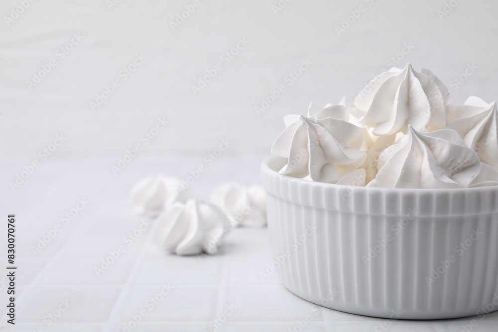 Delicious meringue cookies in bowl on white tiled table, closeup. Space for text Delicious meringue cookies in bowl on white tiled table, closeup. Space for text