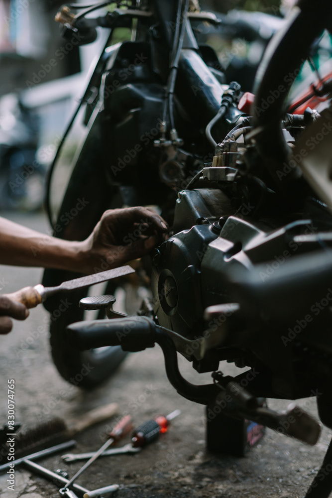 A motorcycle mechanic inspecting a damaged engine A motorcycle mechanic inspecting a damaged engine