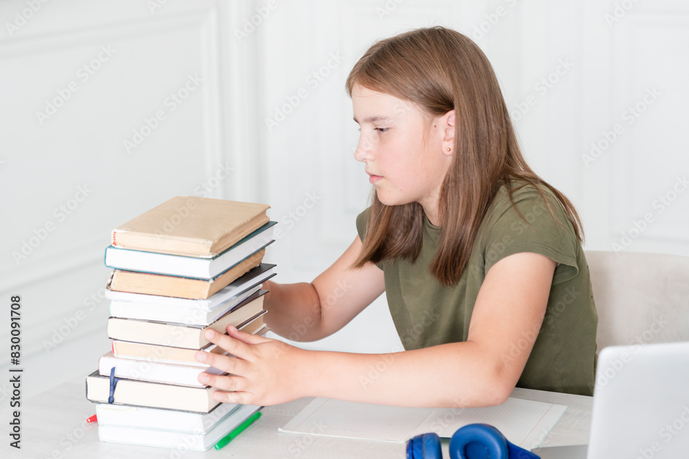 Portrait of lovely school girl sitting at the table and studying online. Distance education and preparation for school concept Portrait of lovely school girl sitting at the table and studying online. Distance education and preparation for school concept