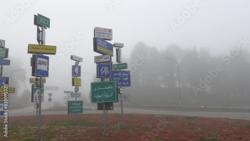 Almhult, Sweden A traffic circle in the fog with road signs in multiple languages including Russian, Thai, and Arabic. photo