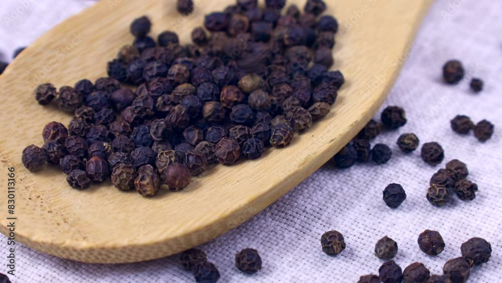 Black pepper peppercorns falling down into the spoon close up Black pepper peppercorns falling down into the spoon close up